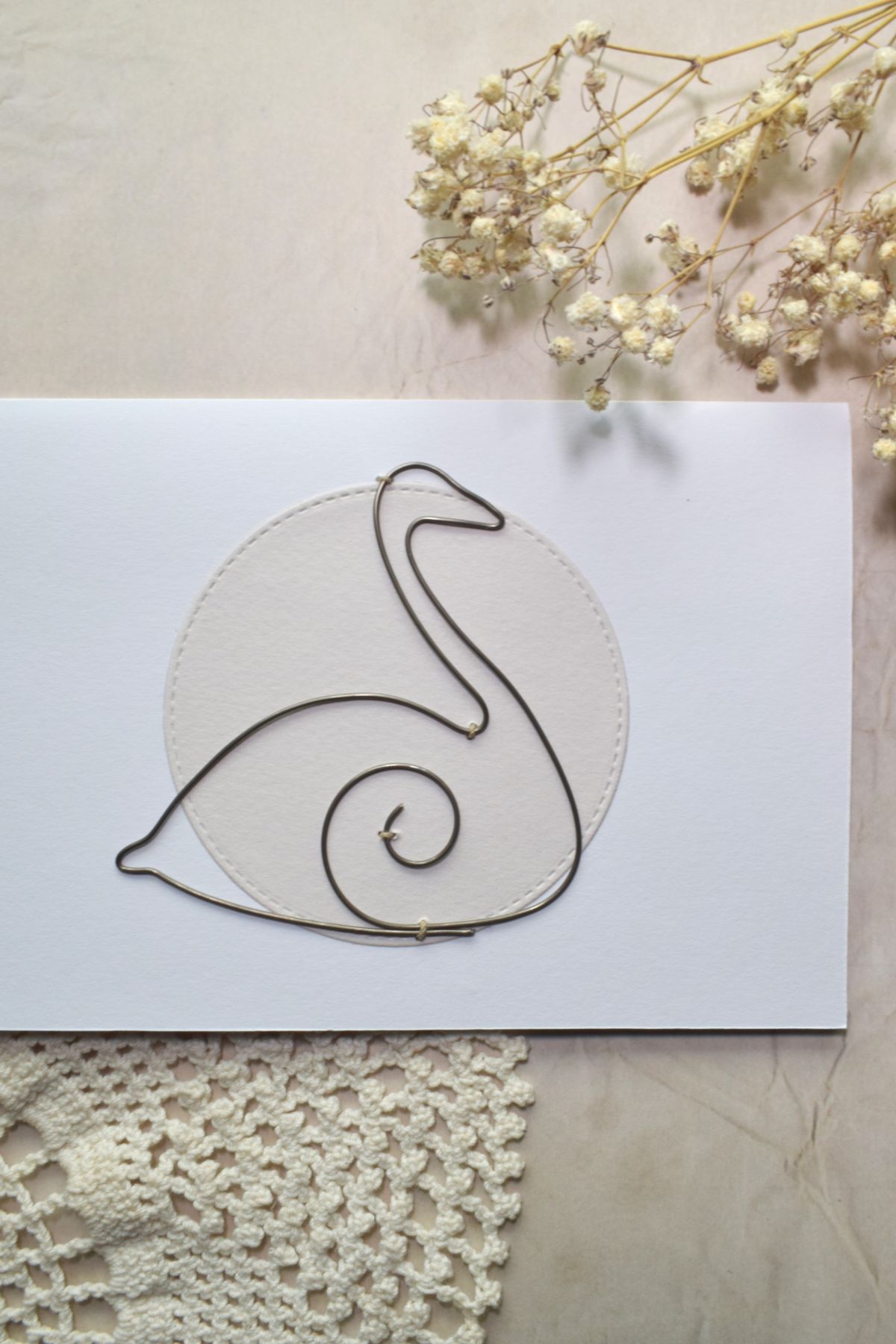 Kortin koristeena on rautalangasta muotoiltu joutsen